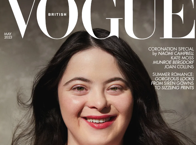 Imagem com fundo cinza, escrito vogue em branco. com a foto de modelo branca de cabelos castanhos compridos, com síndrome de down sorrindo